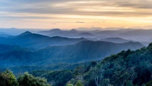 Montañas cubiertas de bosque bajo un cielo de amanecer, con bruma entre los valles